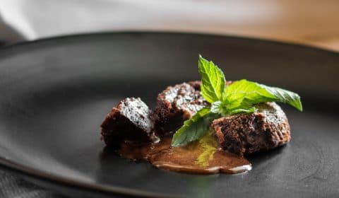 A photo of chocolate lava cake garnished with a sprig of mint.
