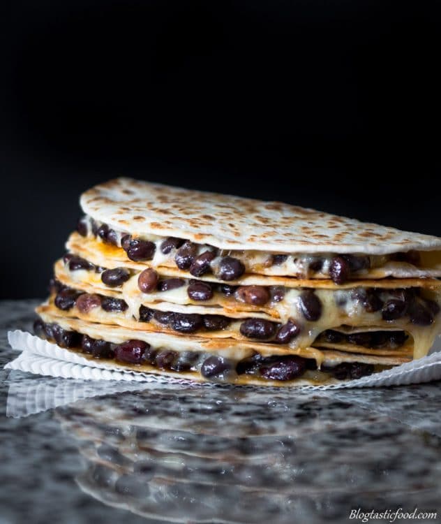 Cheesy spiced black bean filled quesadillas stack on top of one another.