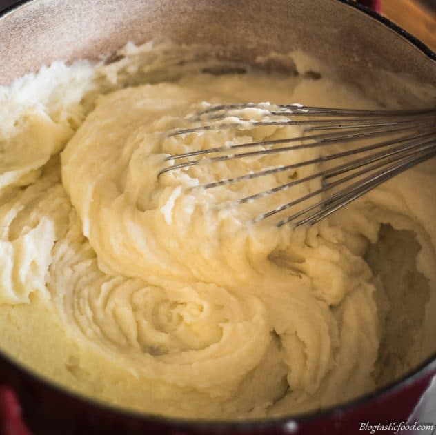 Potato puree being whisked in a pot. 