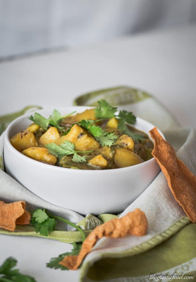 A bowl of potato and green bean curry with poppadoms. 