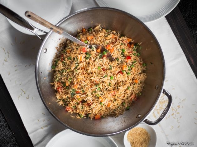 An overhead photo of fried rice in a wok surround by plates ready to be served.