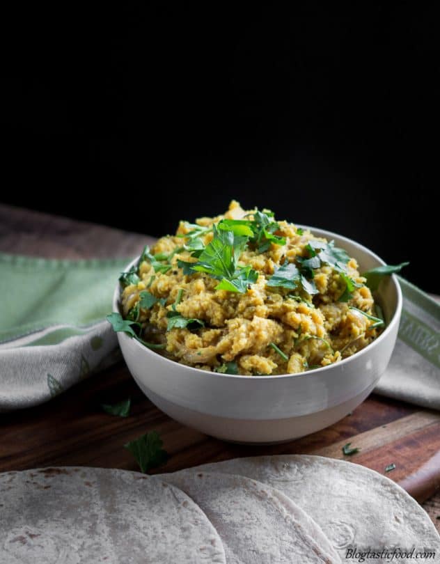 A contrast photo of red lentil dhal garnished with fresh coriander.