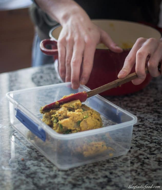 Red lentil dhal being transferred to a plastic container.