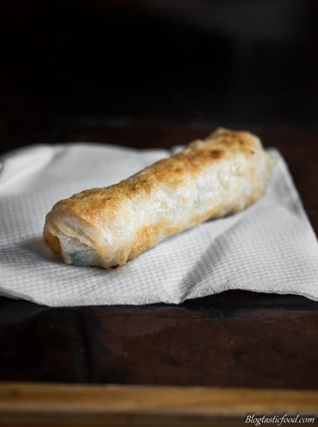 A shallow fried Vietnamese spring roll draining on kitchen paper.