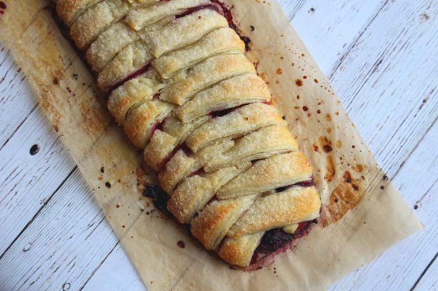 An overhead photo of vegan berry and brie strudel on a sheet of baking paper. 