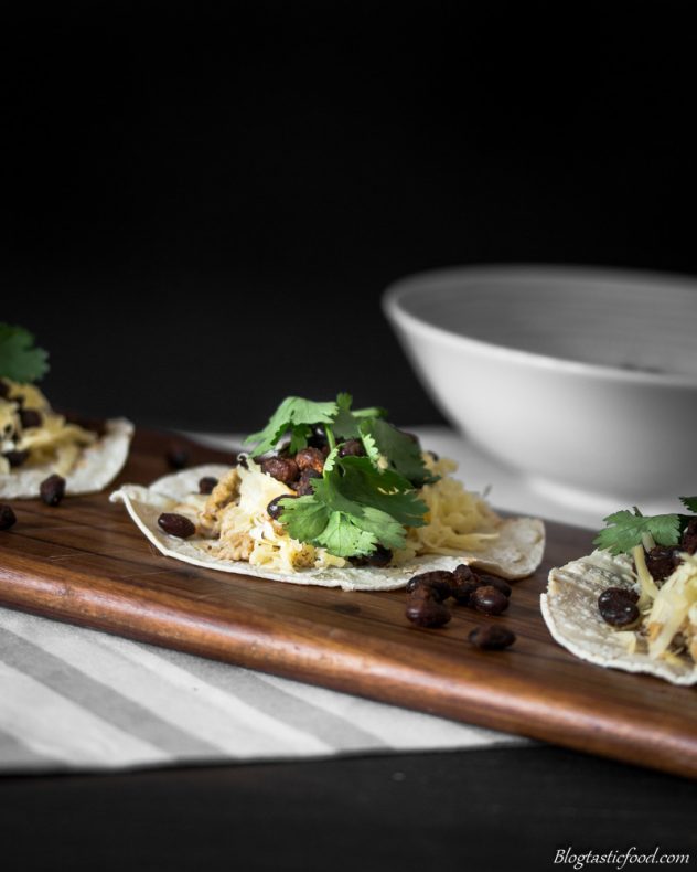 Spiced black bean and scrambled egg breakfast taco served on a wooden board.