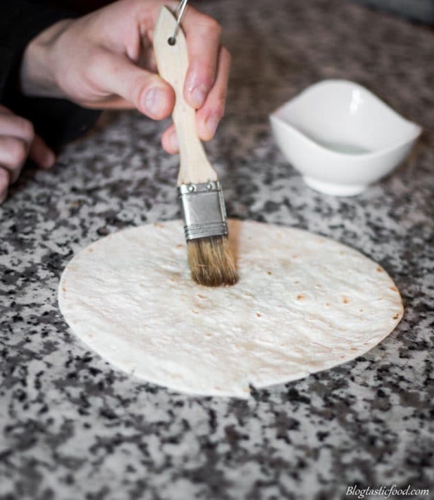 A photo of someone brushing oil on a plain tortilla.