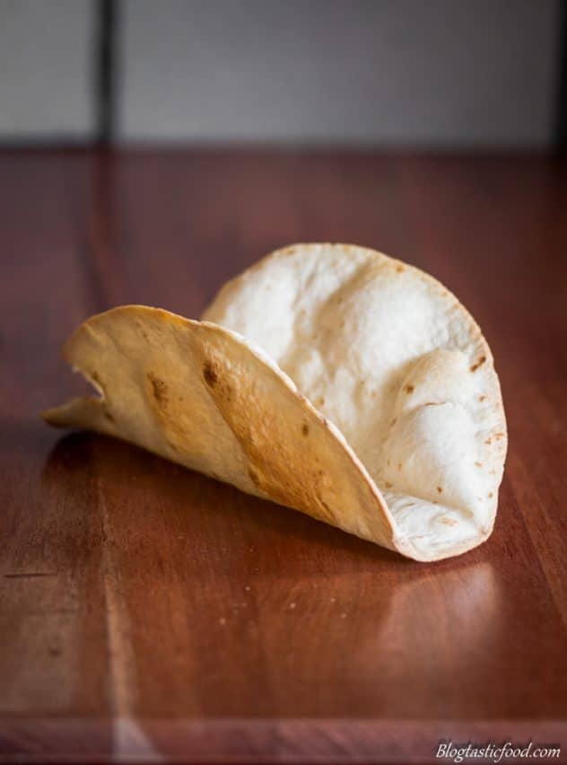 A photo of a hard taco shell on a wooden surface.