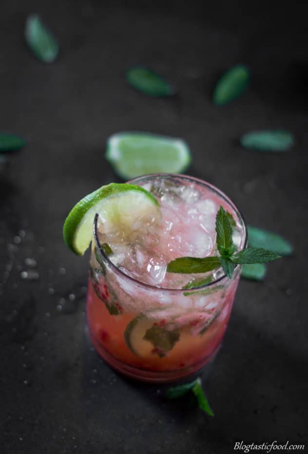 A photo of strawberry mojito that has been garnished with a lime wheel and a sprig of mint.