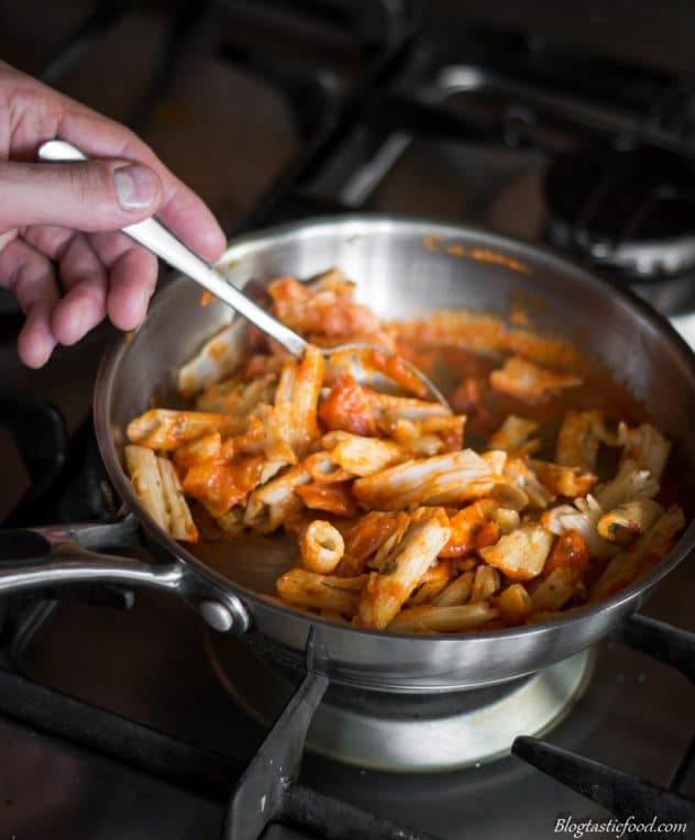 Pasta being tossed through red pepper and tomato sauce. 