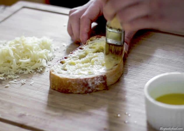 Melted butter being brushed over a slive of bread.