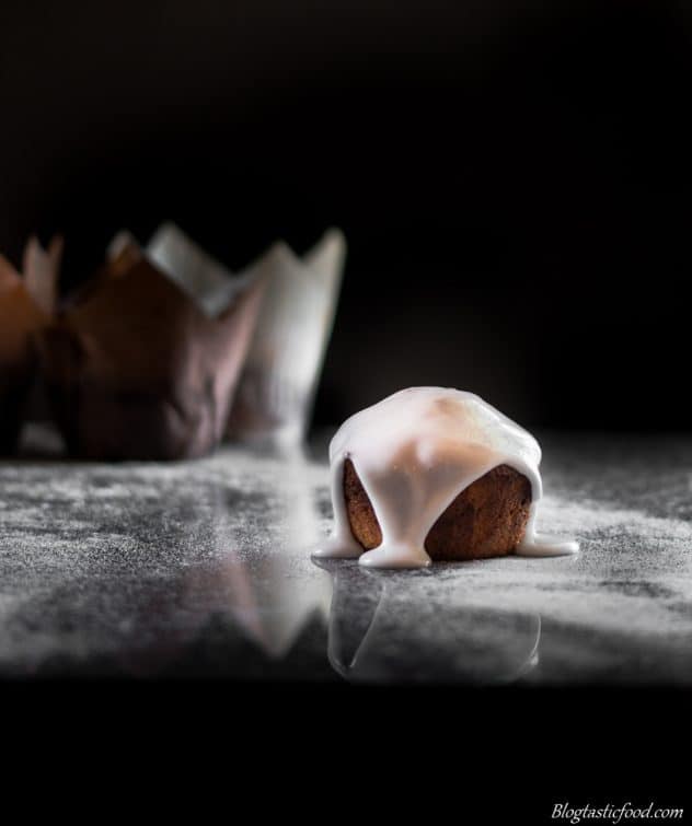 A dark moody photo of a coconut, poppyseed and lemon drizzle muffin.