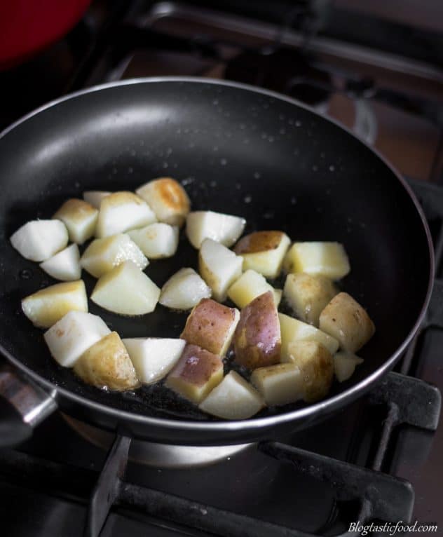 A photo of par-boiled potatoes being pan fried in a non-stick fry pan.