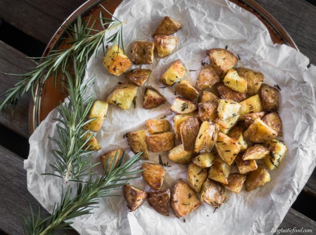 An overhead photo of roasted potatoes on a roasting tray lined with baking paper.