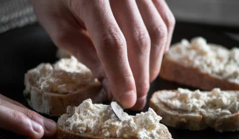A photo of ricotta cheese being spread over