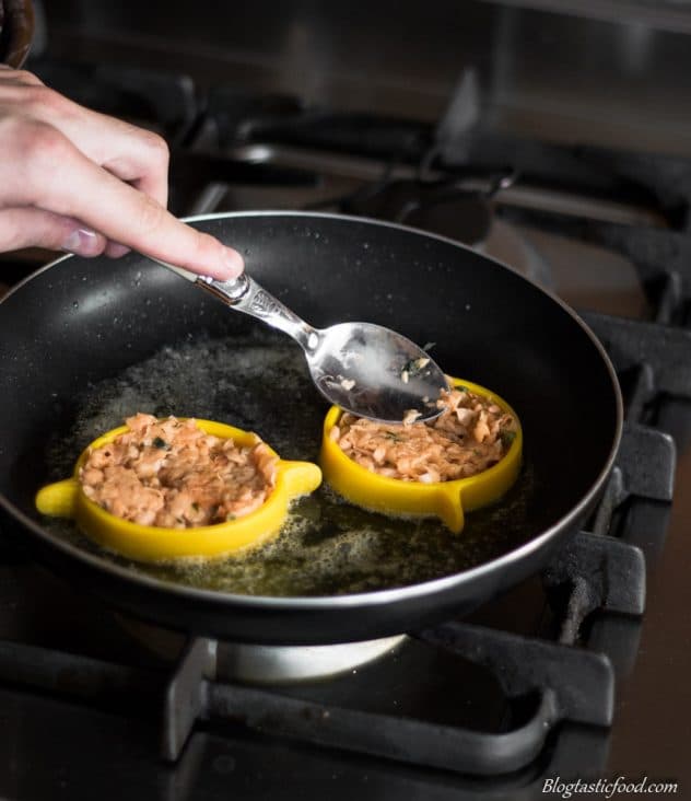 A photo of someone using an egg ring to fry hash browns in a non-stick pan.