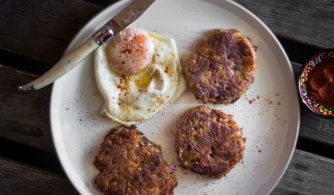 A overhead photo of a fried egg and 3 hash browns served on a plate.