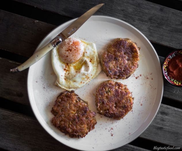 A overhead photo of a fried egg and 3 hash browns served on a plate.