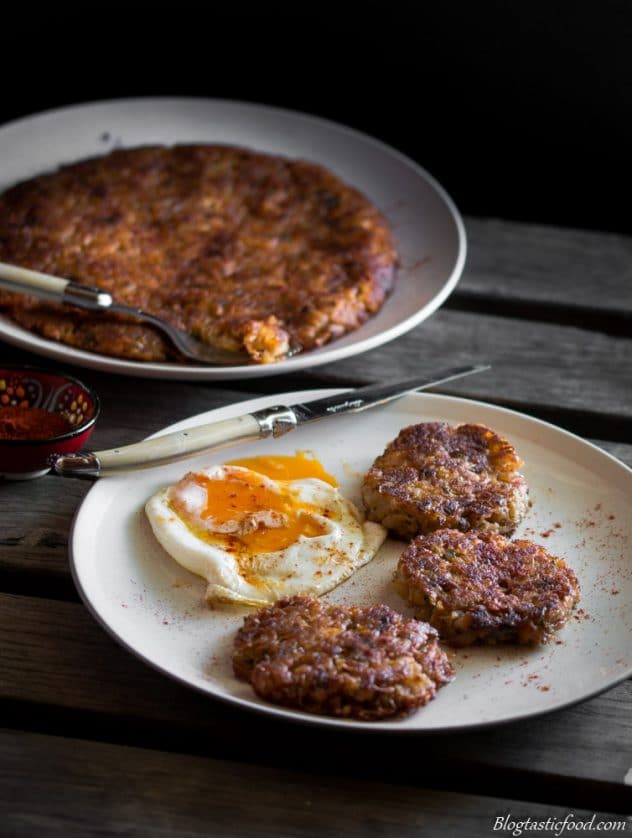 A dark, moody photo of a fried egg and hash browns.