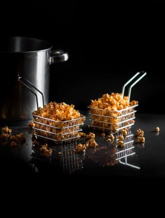 A dark. moody photo of savory spiced popcorn in metal baskets.