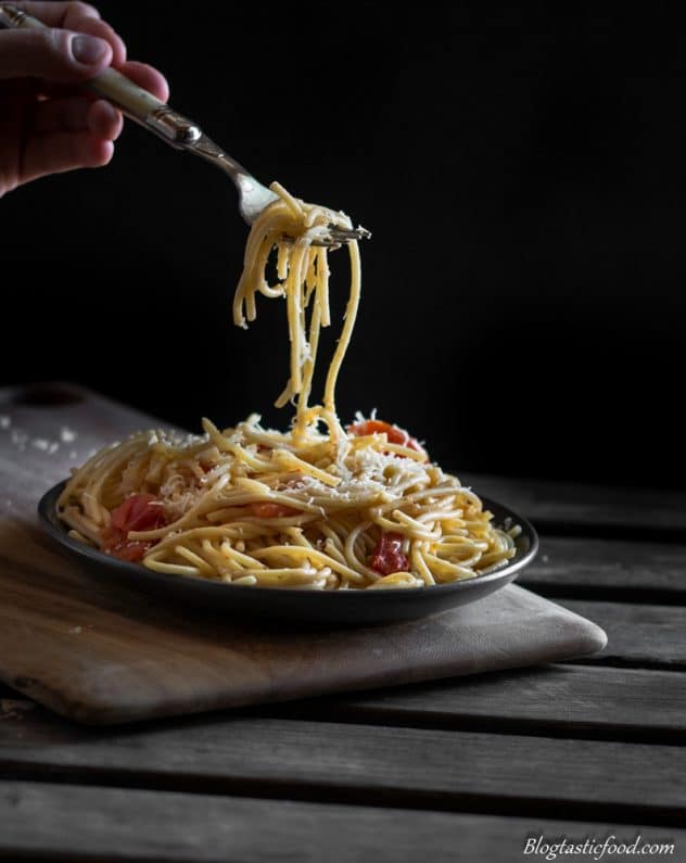 A photo of someone using a fork to lift up some pasta off of a plate.