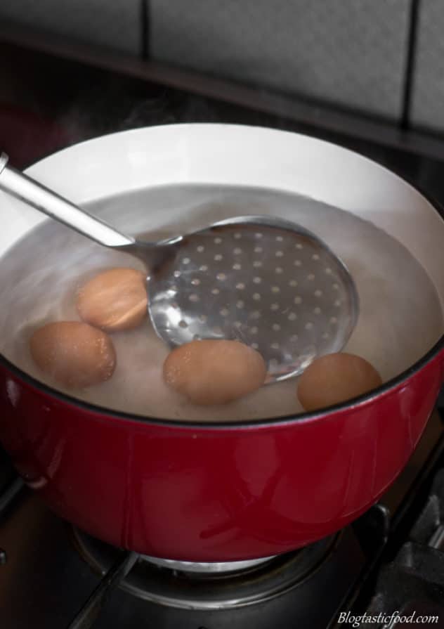 A photo of someone gently stirring some eggs in a pot as they boil.