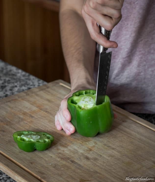 Someone cutting out the core of a bell pepper.