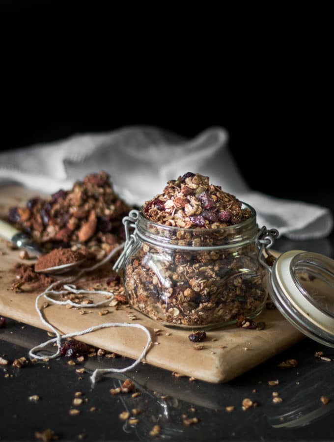 A dark and moody photo og a glass jar filled with chocolate flavoured granola mix.