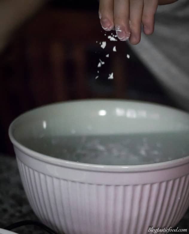 A photo of someone sprinkling creme of tartar into a bowl of meringue.