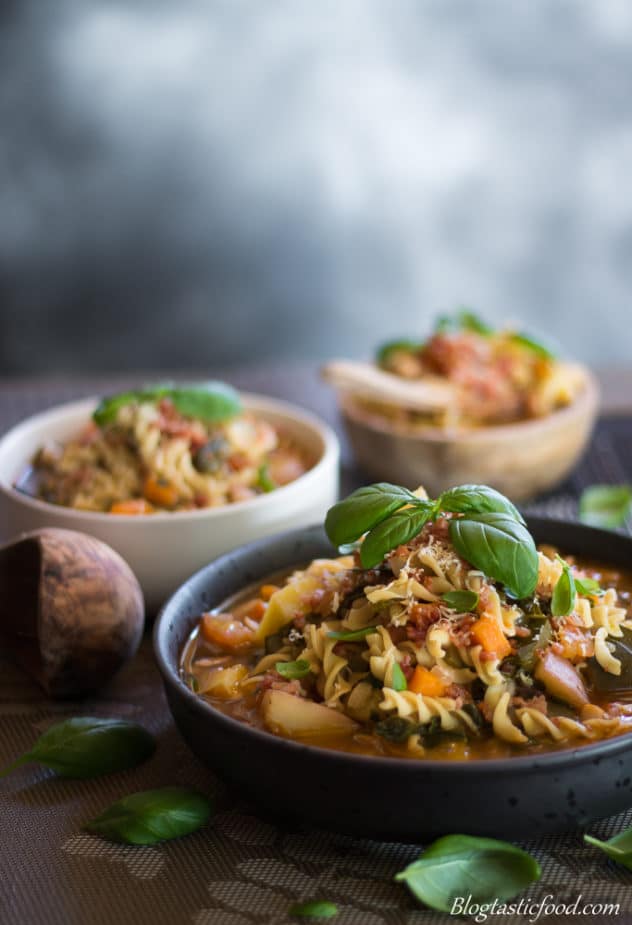 bowls of minestrone soup that have been garnished. 