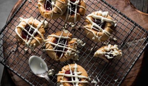 An overhead photo of white chocolate drizzle peanut butter and jam cookies on a cooling rack.