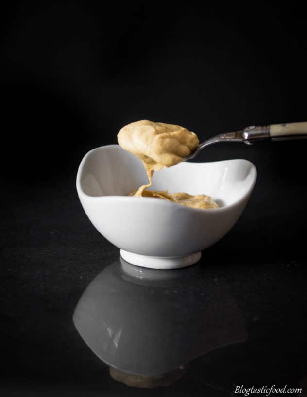 A photo dijon mustard on a spoon and in a small bowl.