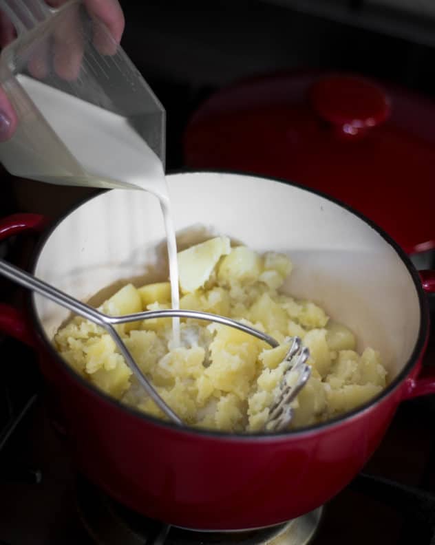 A photo of milk being added to mashed potatoes 