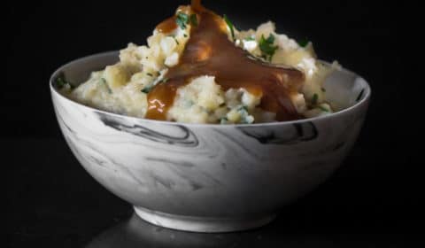 Gravy being poured over a bowl of mashed potatoes.