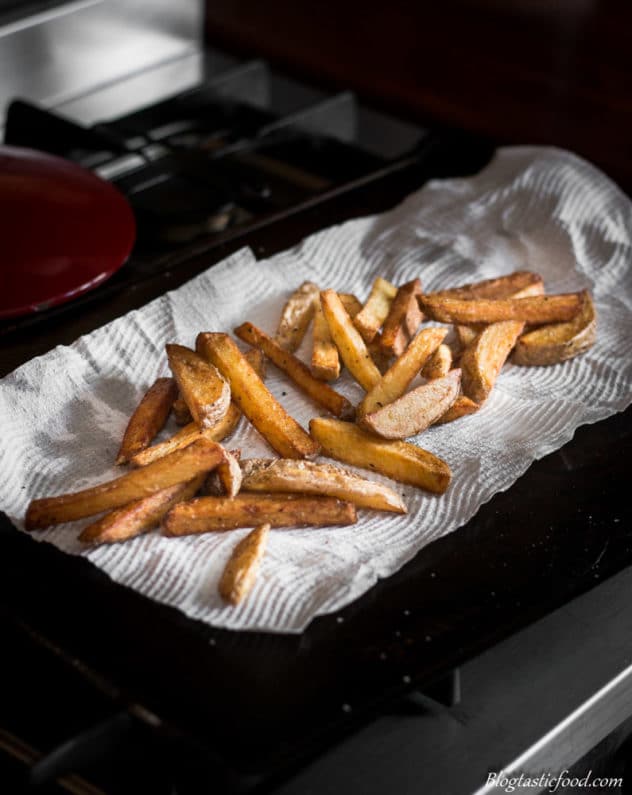 A photo of chips that are draining on kitchen paper.