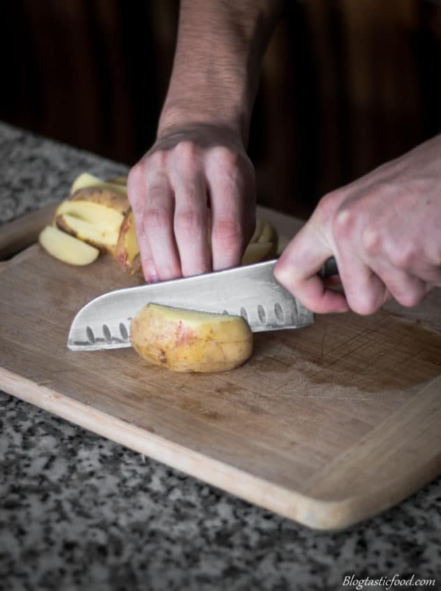 A photo of raw potatoes getting cut into chips.