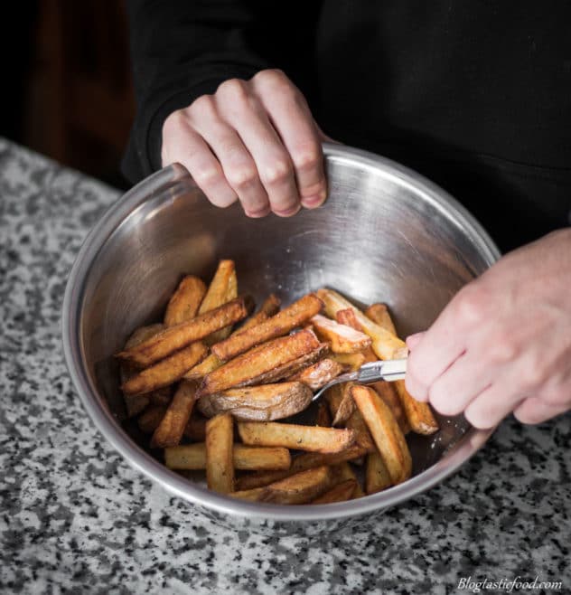 A photo of someone mixing chips through a bowl of salt and pepper.