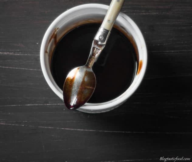The back of a spoon that has just been dipped in balsamic glaze, clearly showing how a finger just swiped on the spoon.