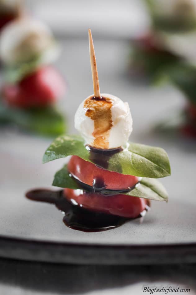 A close up of a mini salad skewer, that has just had balsamic glazed poured on top.
