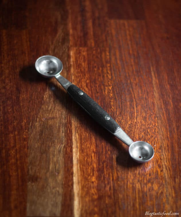 A photo of a ball spoon on a wooden surface. 