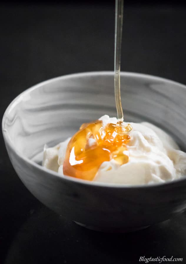A photo of honey being drizzled over ricotta cheese in a bowl.