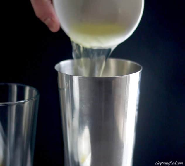 A photo of an egg white being added to a cocktail shaker. 
