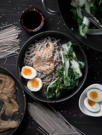 An overhead photo of soba noodles, peanut sauce, bok choy and a boiled egg in a bowl.