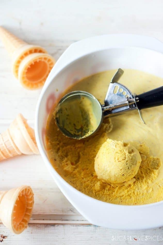 Turmeric, ginger, honey no churn ice cream in a large bowl being scooped.