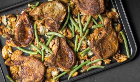 An overheaf photo of baked, curried pork chops and potatoes with green beans on a tray.