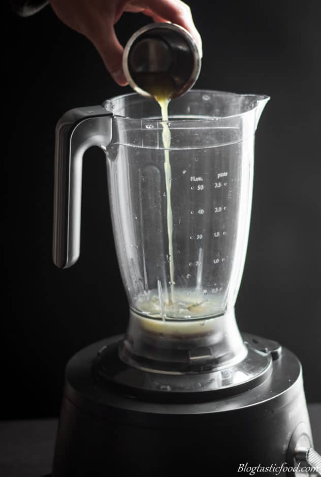 A photo of someone adding orange juice to a blender.