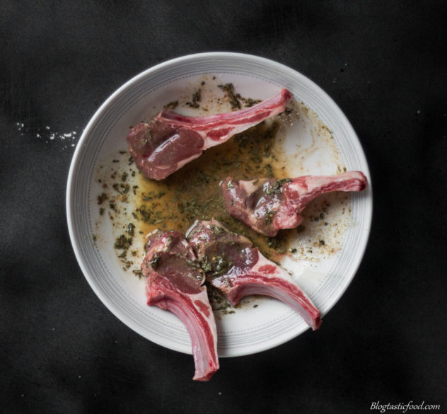 A photo of 4 lamb cutlets in a bowl marinating in a rosemary, olive oil and lemon marinade.
