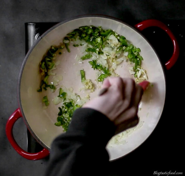 A photo of garic, ginger, onion and green chilli frying on a pot. 