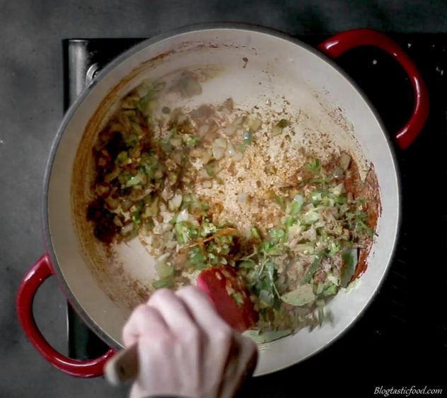 A photo of aromatics and spices being stirred in a hot pot. 