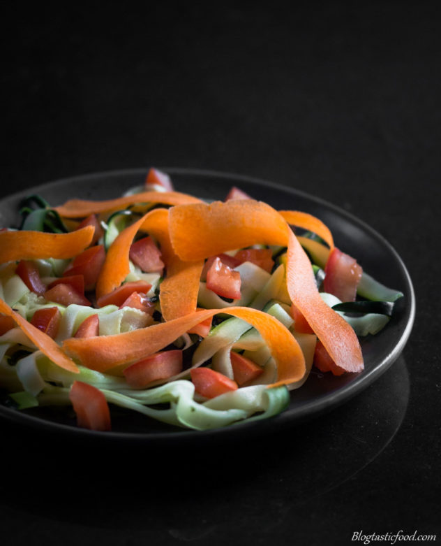 A photo of a simple salad made with zoodles, tomatoes and slithers of carrot.